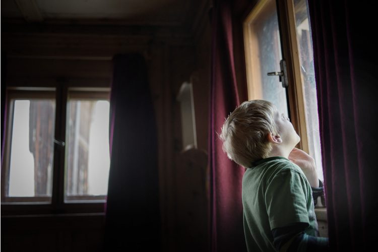 Duri listens pensively to the sound of the church bells in his living room at home.