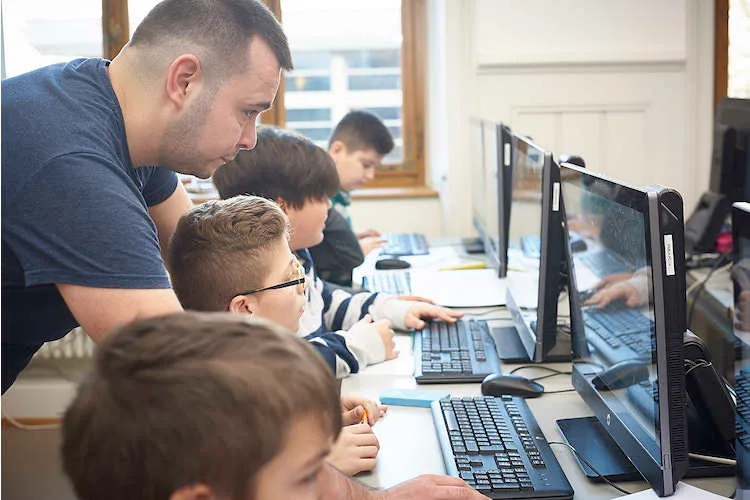 Informatikstudent Yasin Oytun hilft Basler Schülern der Primarschule Bläsi im Rahmen des Projekts Primalogo beim Erlernen der Programmiersprache. Wir haben sie besucht – die Reportage.