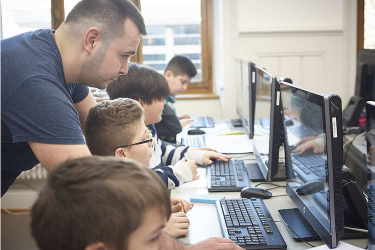 Informatikstudent Yasin Oytun hilft Basler Schülern der Primarschule Bläsi im Rahmen des Projekts Primalogo beim Erlernen der Programmiersprache. Wir haben sie besucht – die Reportage.