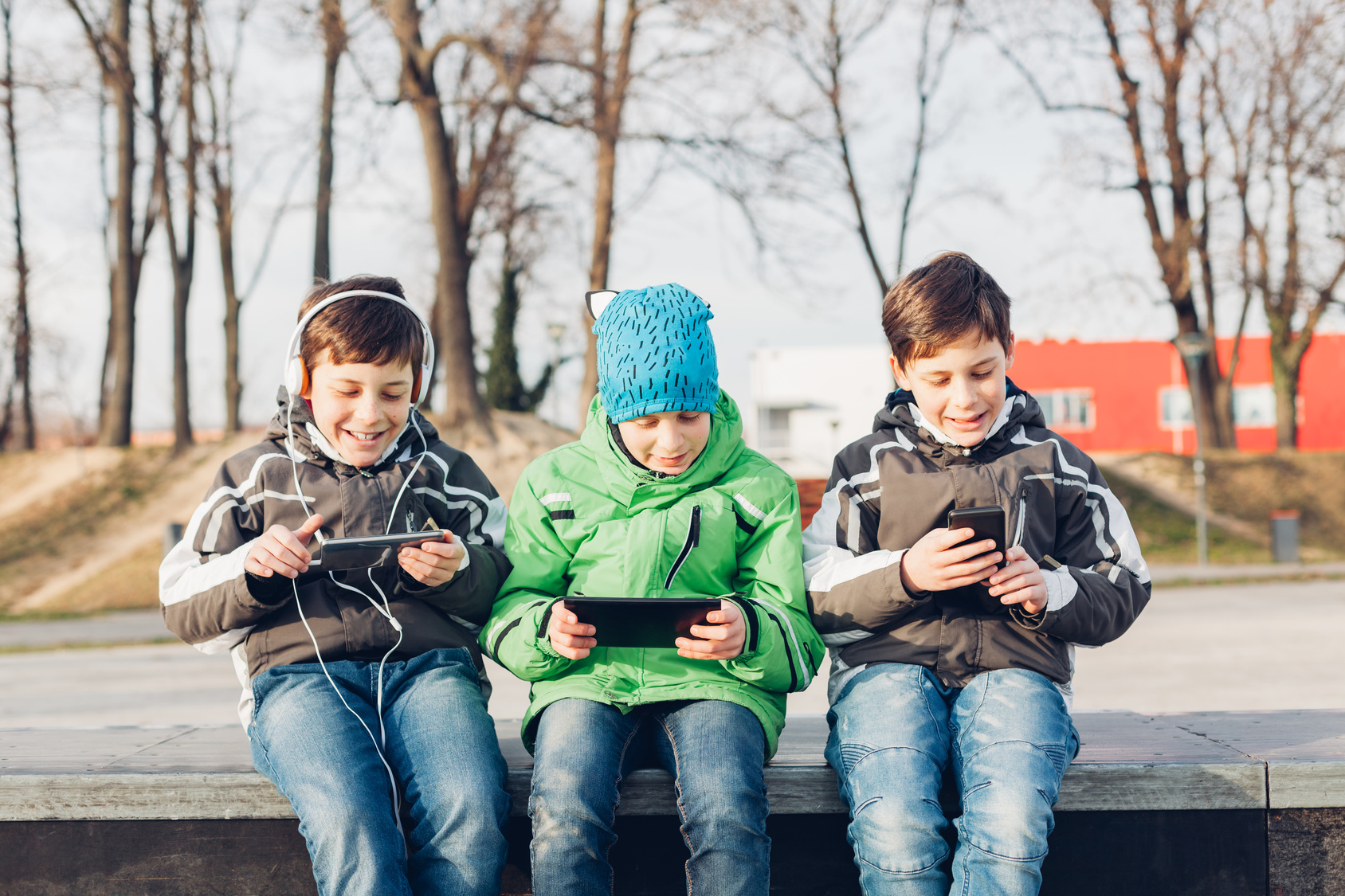 Three boys using mobile phones in the park Outdoor Apps für Kinder