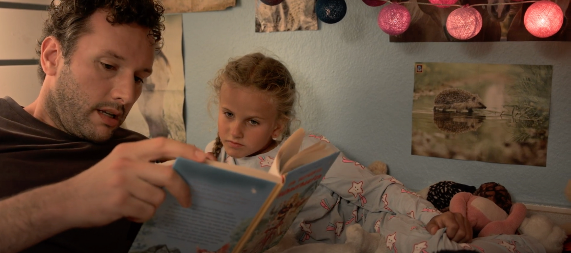 Wenn Eltern ihren Kinder vorlesen. Vater mit Tochter und einem Buch im Bett.