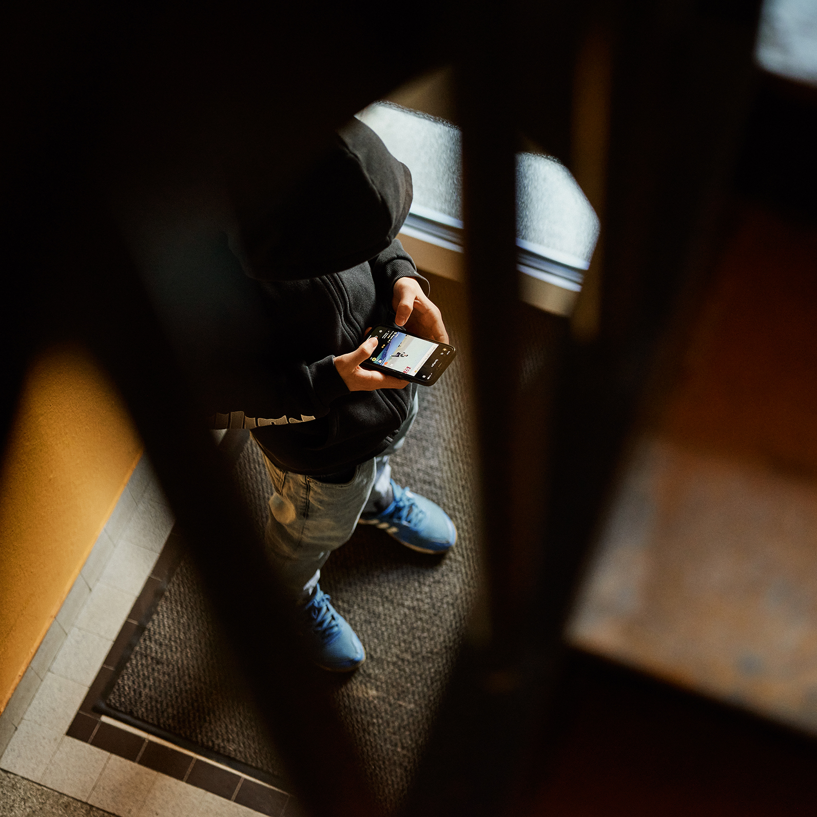 Schulfrust: Junge steht im Treppenhaus mit Handy