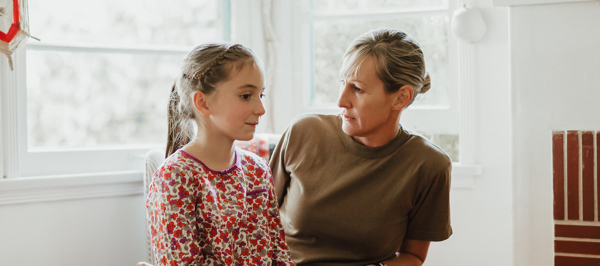 Tochter sitzt auf dem Schoss der Mutter. Verstehen Kinder Ironie?