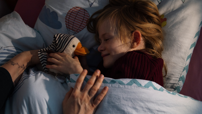 Schlaf: Mädchen mit Stofftier im Bett